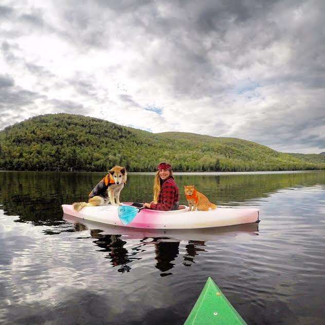 Dog and cat on kayak with young woman