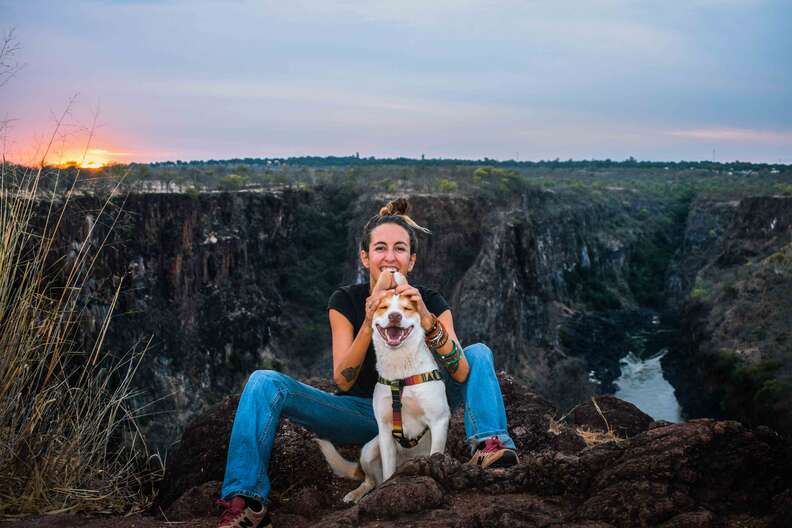 Woman and dog hiking through African bush