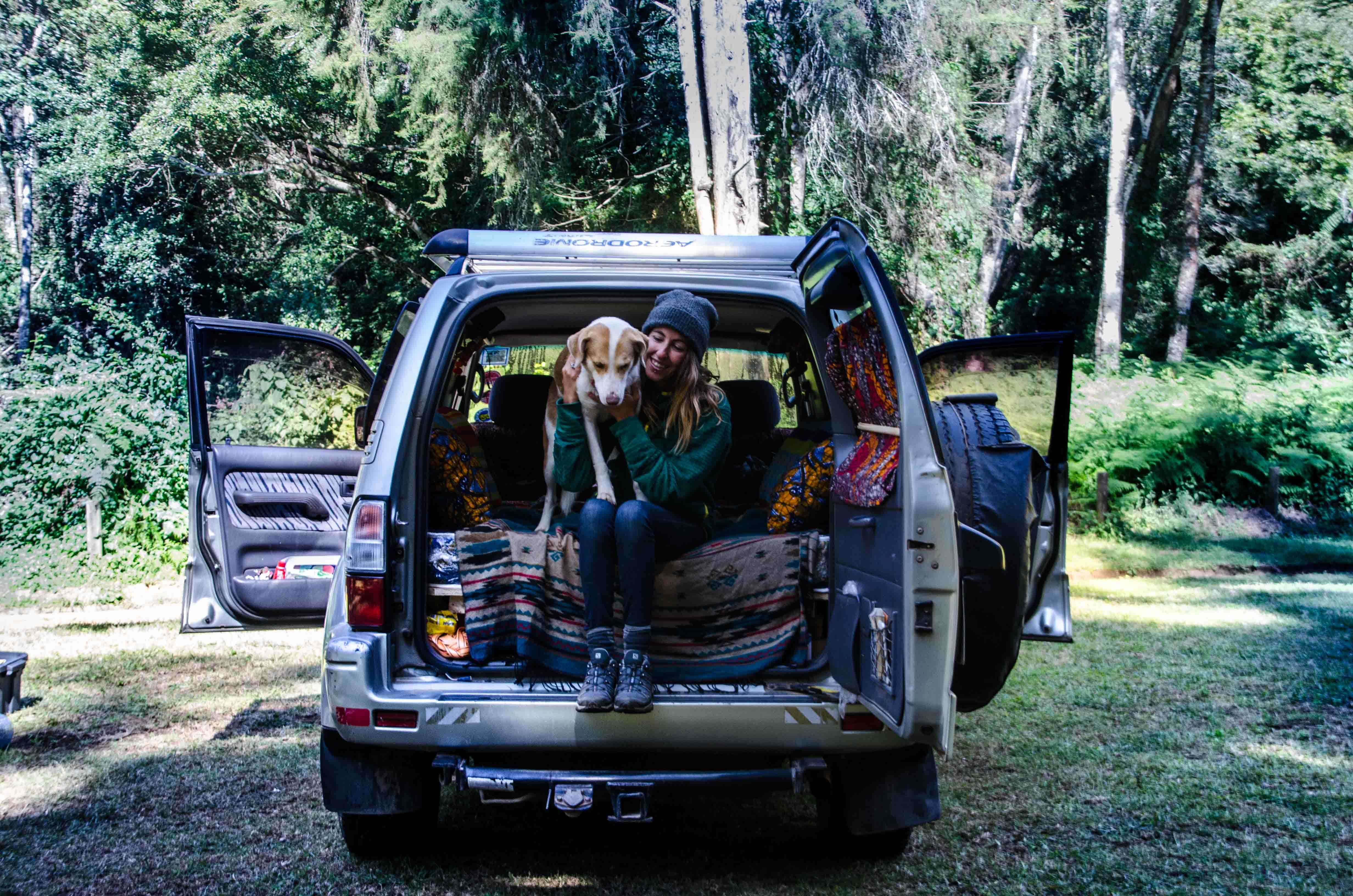 Woman and dog sitting in the back of a vehicle