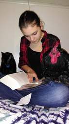Rooster sitting on girl's lap as she reads