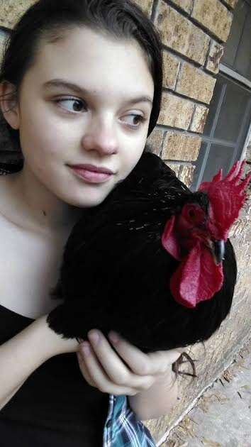 Girl holding rooster against her shoulder