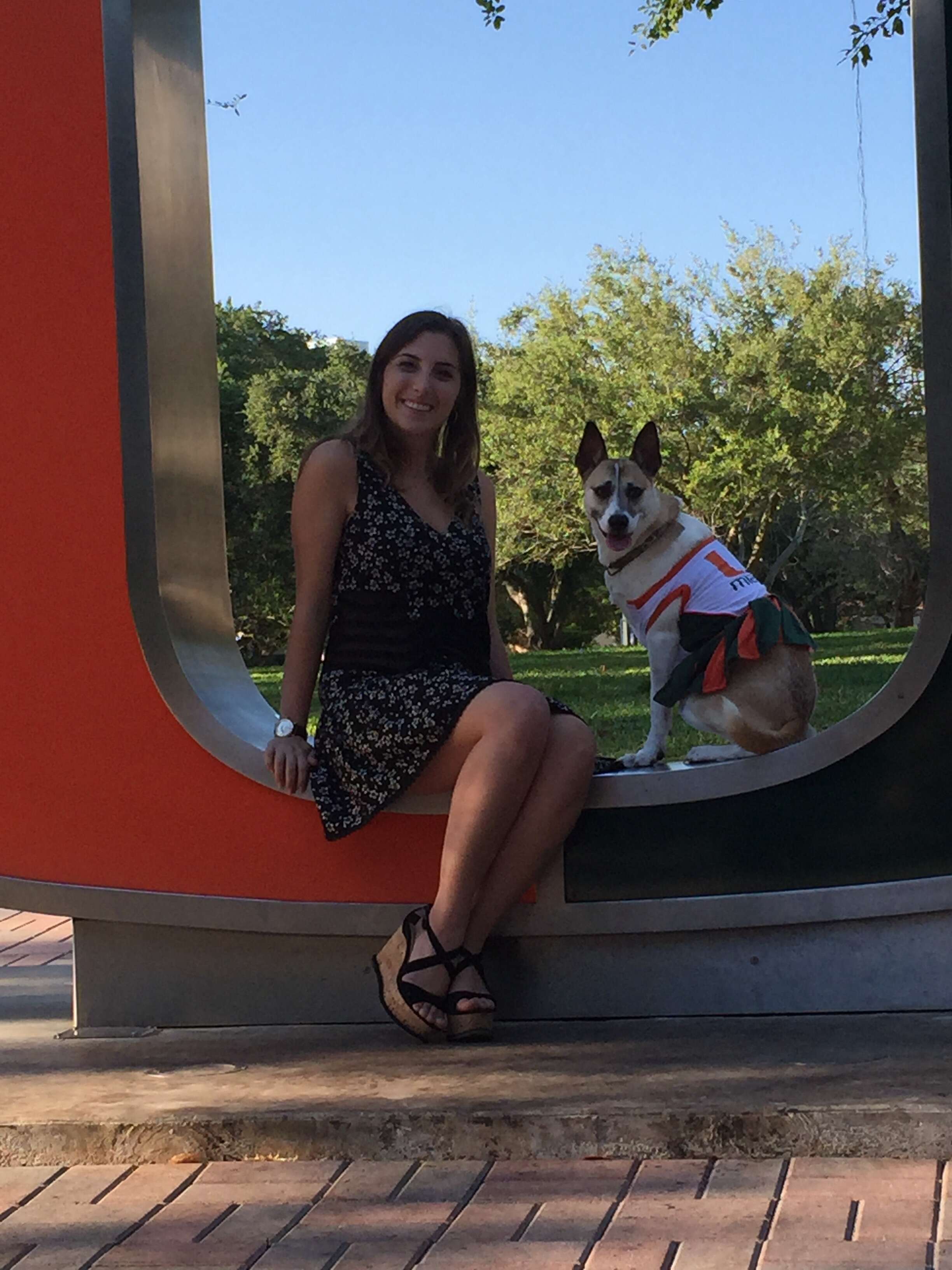 Woman and dog sitting on university sign