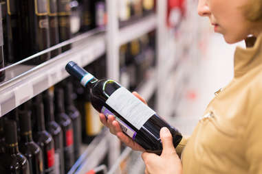 Woman reading back of wine bottle