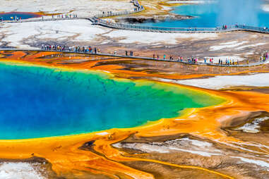 tourists surrounding an enormous colorful natural spring