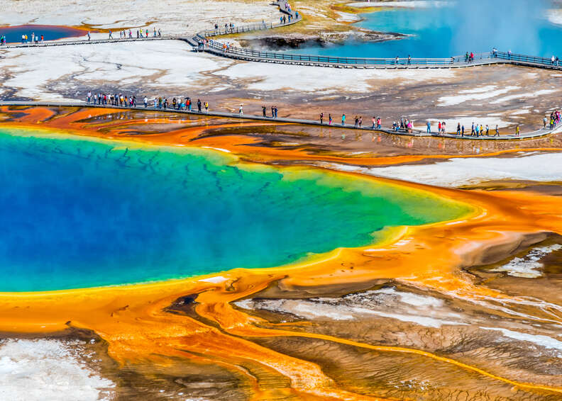 tourists surrounding an enormous colorful natural spring