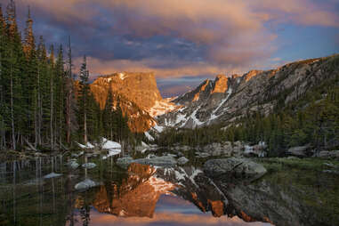 a lake in front of mountains at sunset