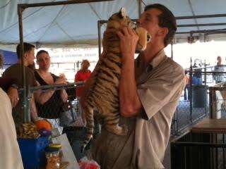 A man holding a tiger cub at a traveling zoo