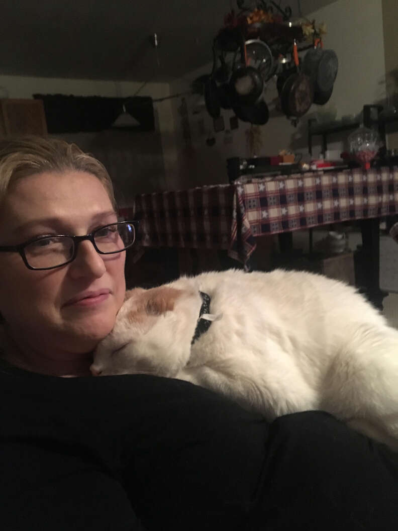 Woman cuddling with cat underneath her chin