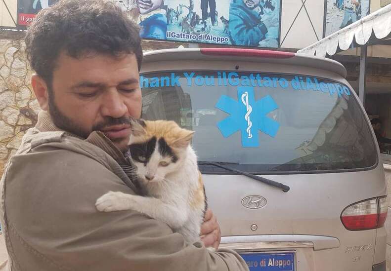 Man holding cat in front of ambulance