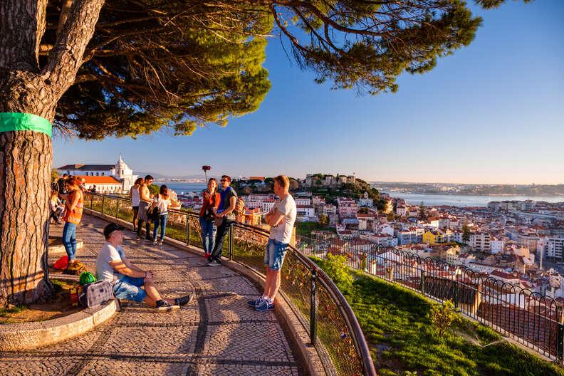 people gathered along a hillside walkway above a beautiful European city