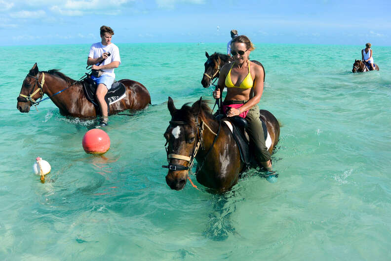 people on horses in the ocean