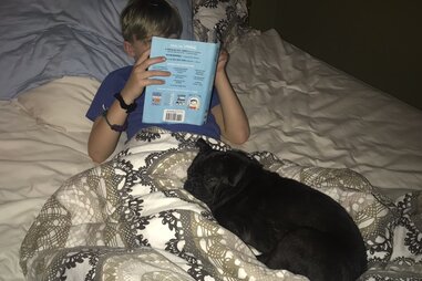 Dex snuggles on a bed with his adoptive family