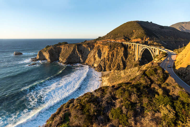 cars on road winding by ocean cliffs