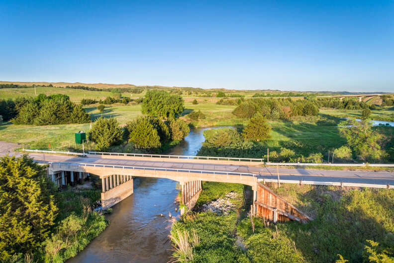 bridge leading over a river near open fields