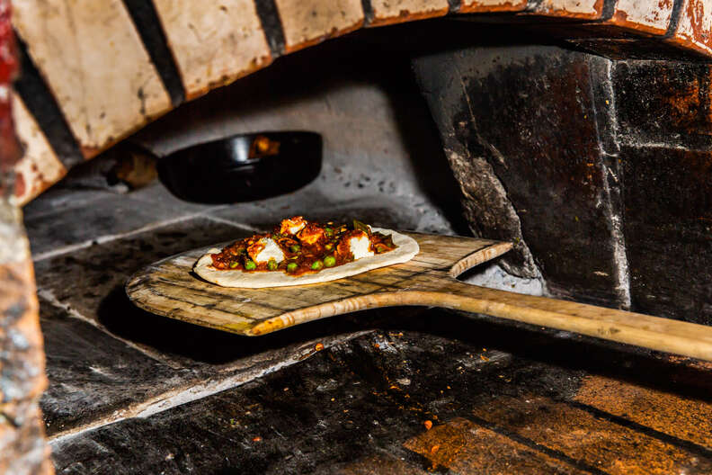 pizza going into the oven, brick oven