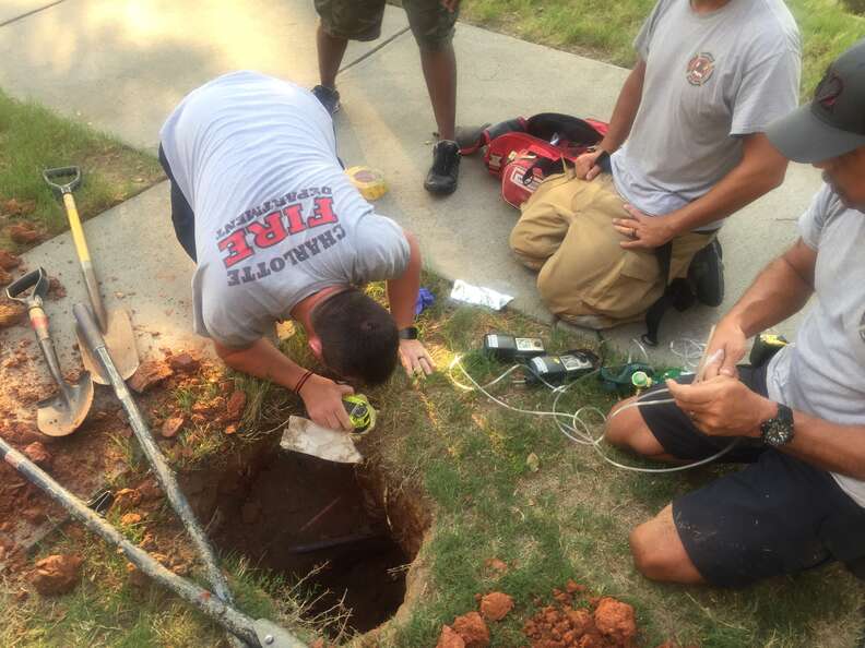 Charlotte fire fighters measure the hole that the puppy fell down