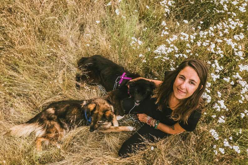Woman sitting in grass with two dogs