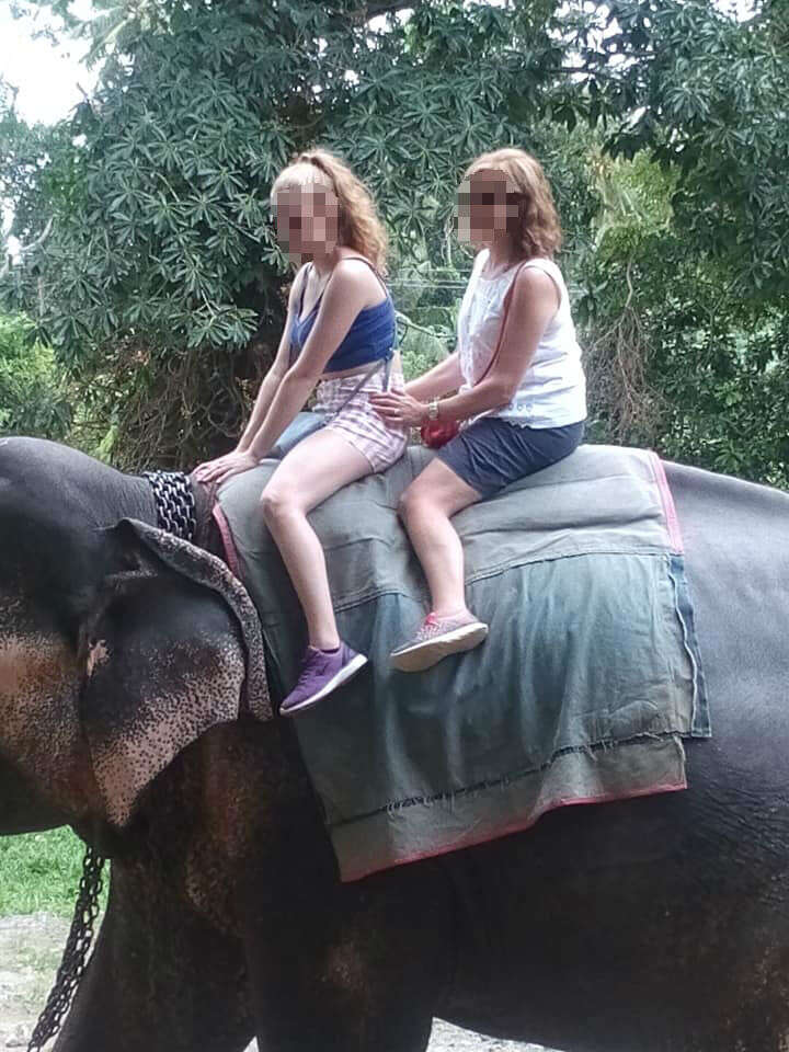Two women riding on the back of an elephant