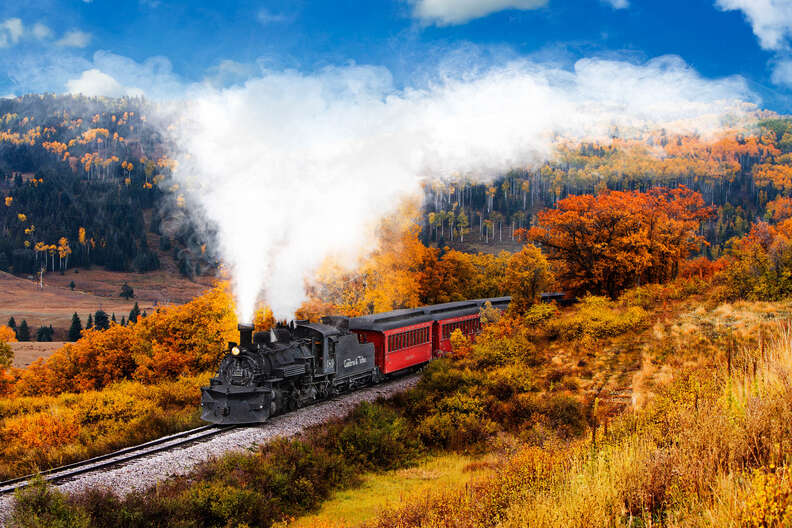 a steam train rolling along through fall scenery
