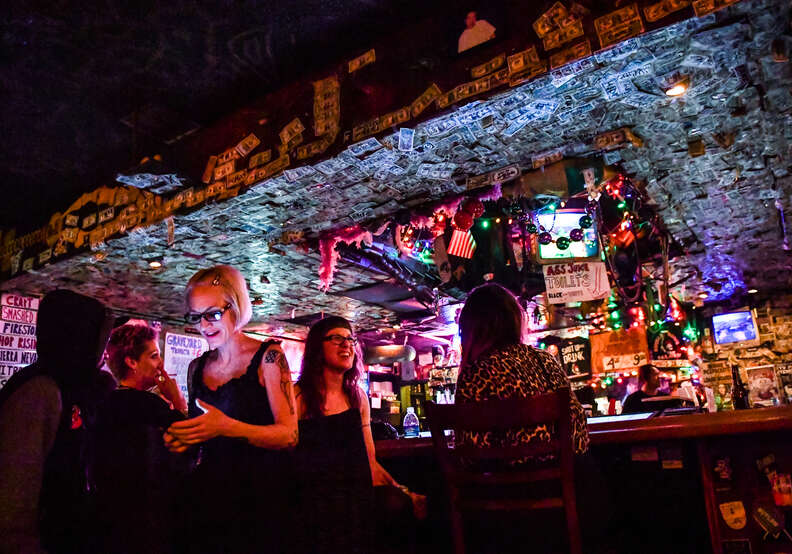 woman checking her phone in a dive bar