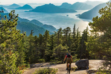 Rear View Of Man Riding Bicycle On Mountain Against Sky