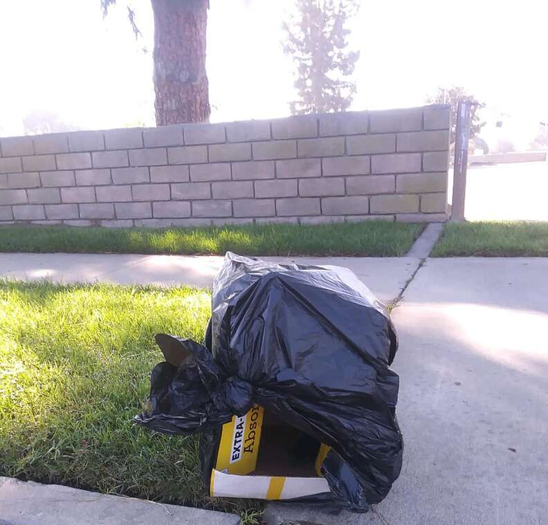 Cardboard box covered in black plastic bag