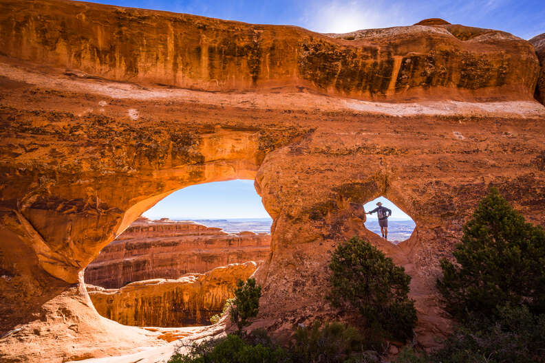 a person standing in the windows of stone arches