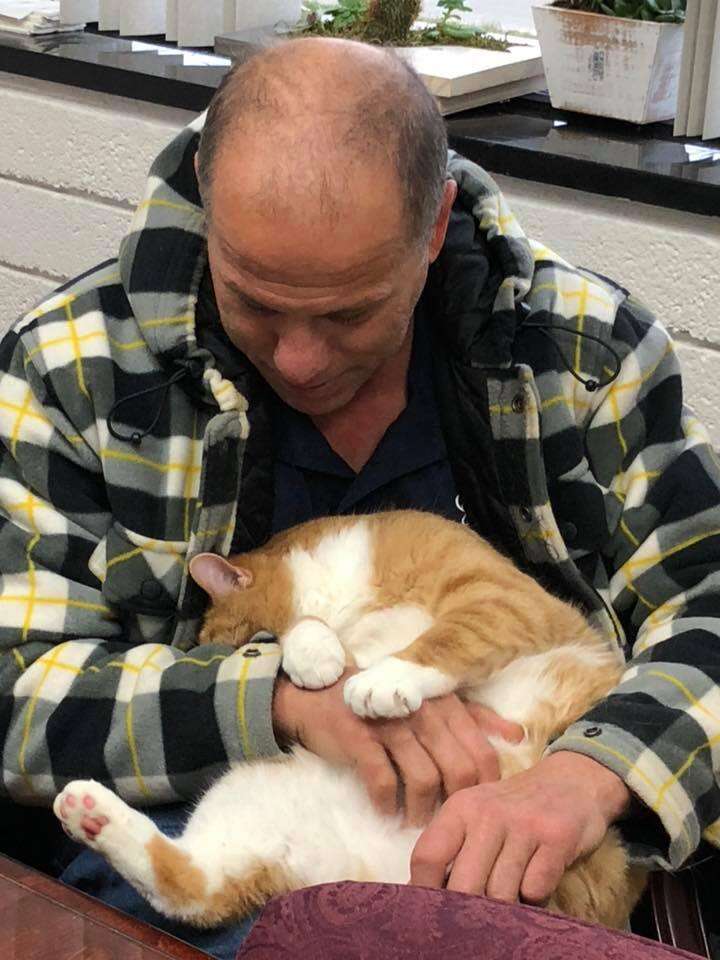 Man cuddling cat in his lap