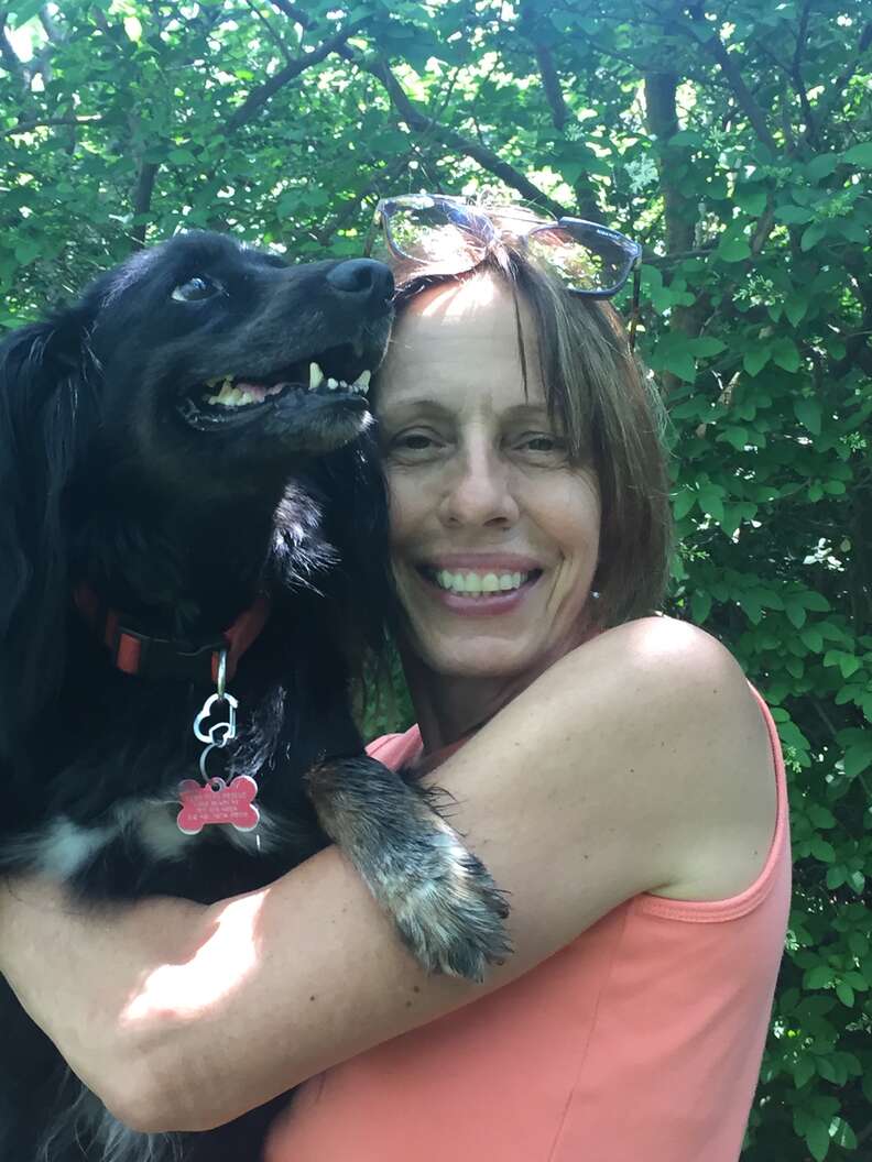 Woman cuddling with black dog