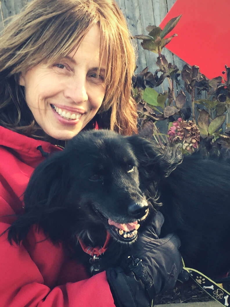 Woman cuddling black dog