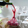 person pouring red wine into decanter