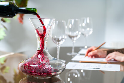 person pouring red wine into decanter
