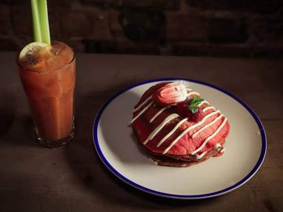 red velvet pancakes topped with tampon-shaped macaron, beside a Bloody Mary in a glass