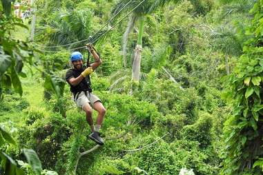 a man smiling as he ziplines in el yunque rain forest 