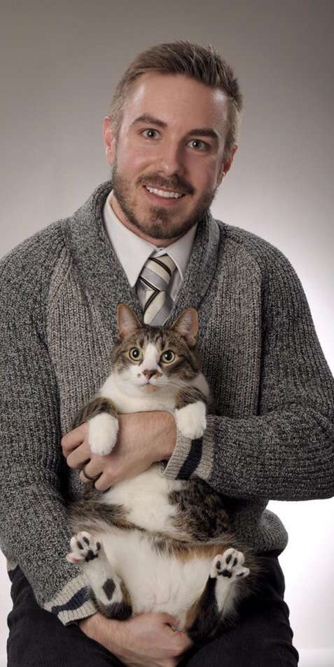 Guy holds cat in graduation photo