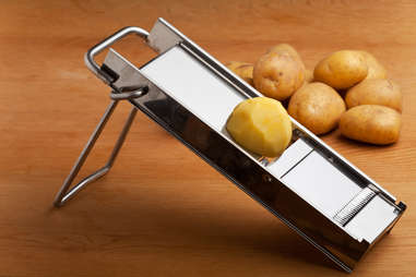 half a potato on a mandolin slicer