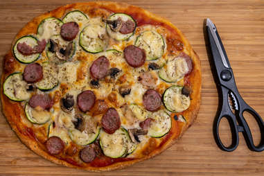 pizza with vegetables and meat and scissors