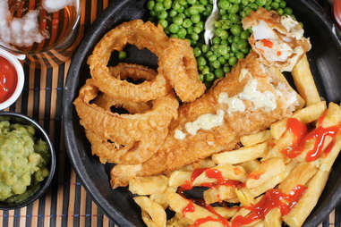 Top down view of an English fish and chips with garden peas, ring onions and mushy peas