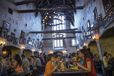 people in a dim dining hall decorated with chandeliers and picture frames