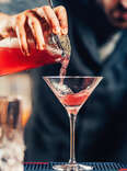 barman pouring cosmopolitan inyo martini glass