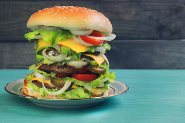 towering burger with many toppings