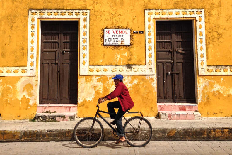 a person riding a bike past a colorful building