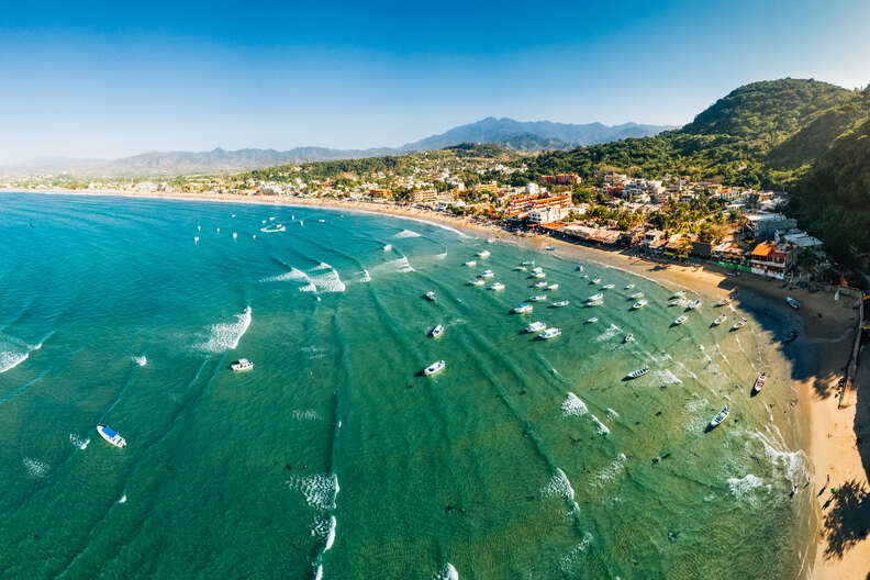 boats off the shore of a seaside hill town