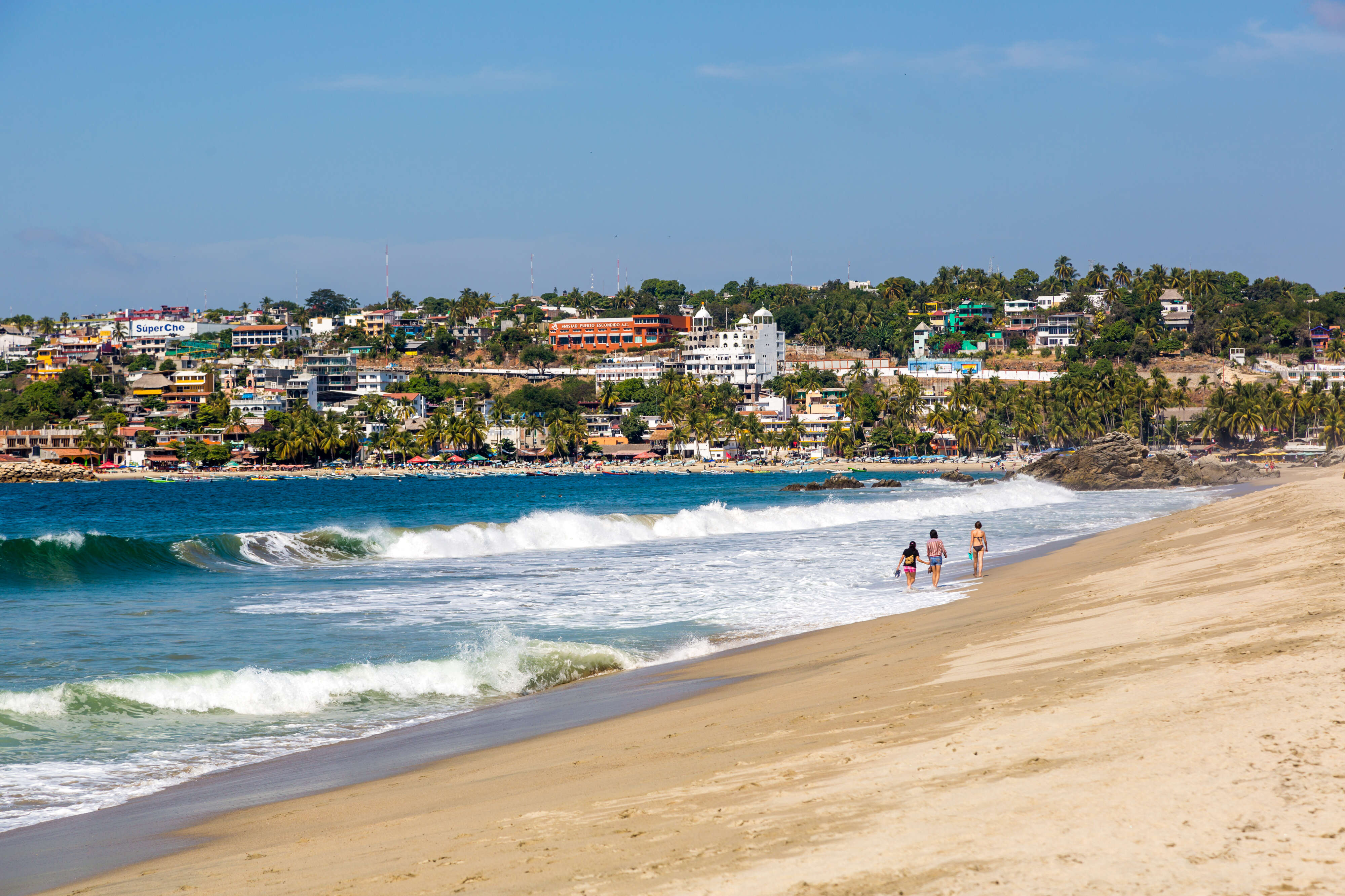 people walking on the beach near a seaside town