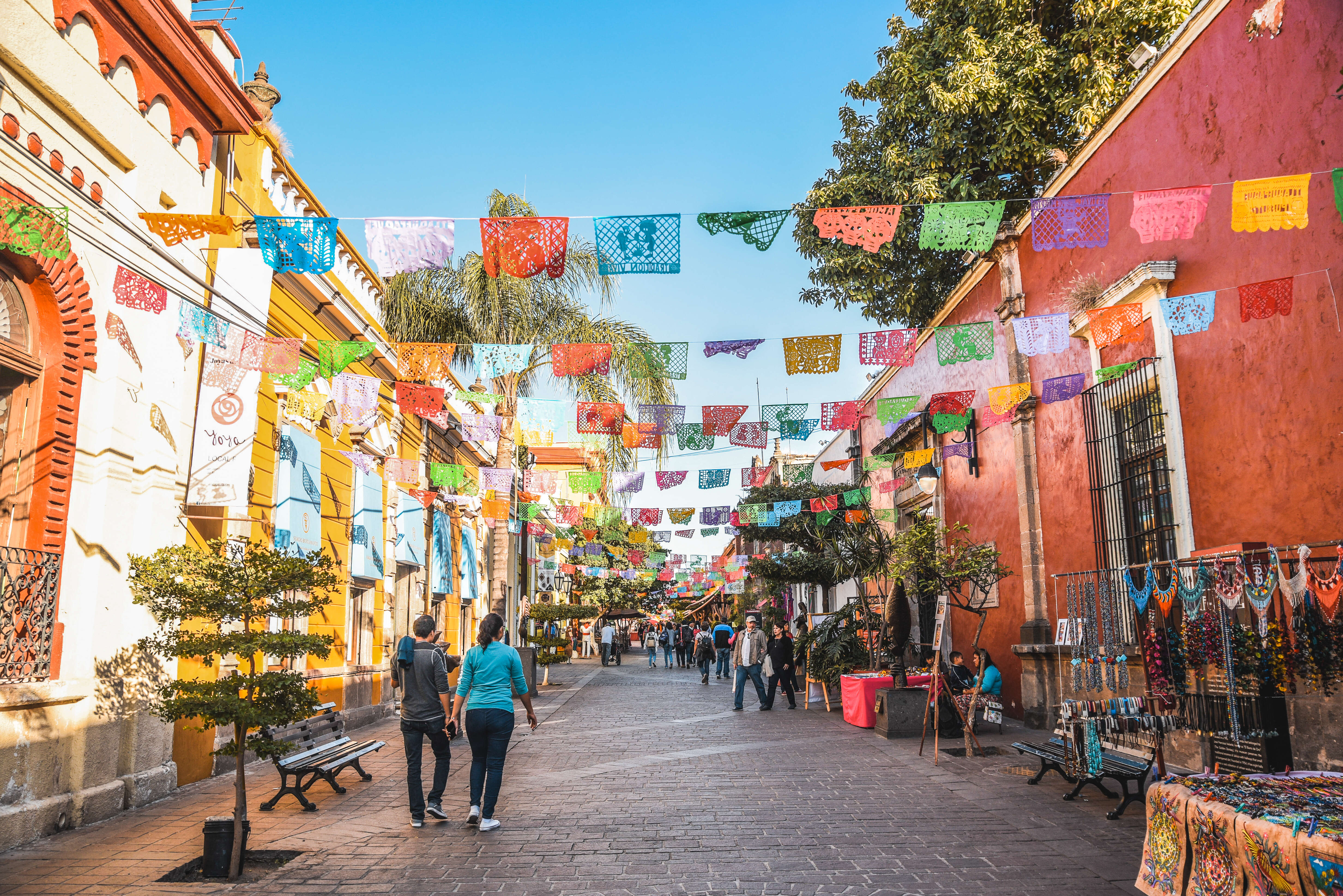 people walking a laneway decorated with paper flags