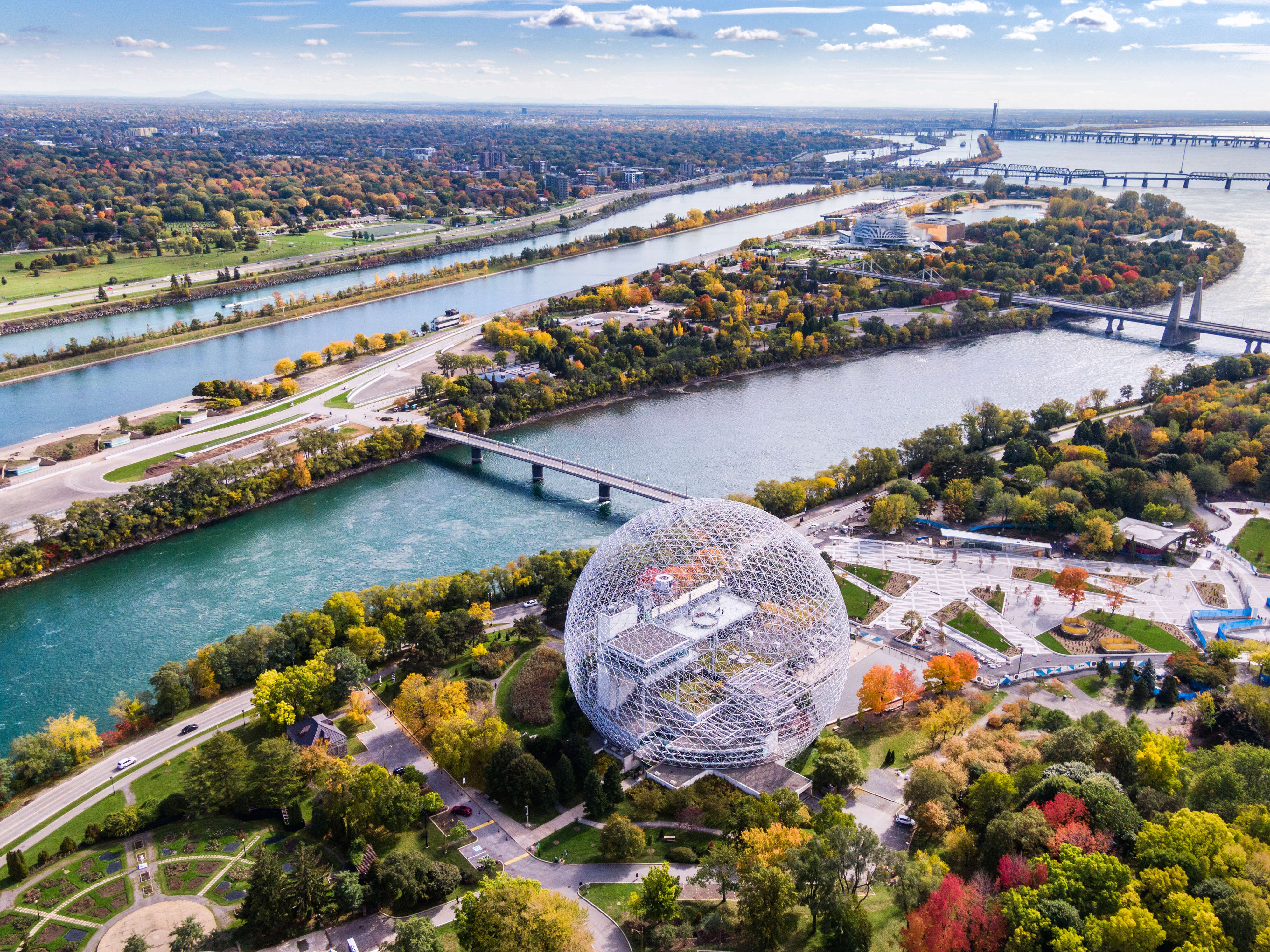 buildings and a large circular structure on a riverbank in fall