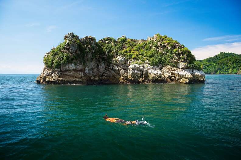 snorkeler diving near a tortoiseshell-shaped island