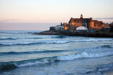 a castle-like hotel on the cliffs above a beach at sunset