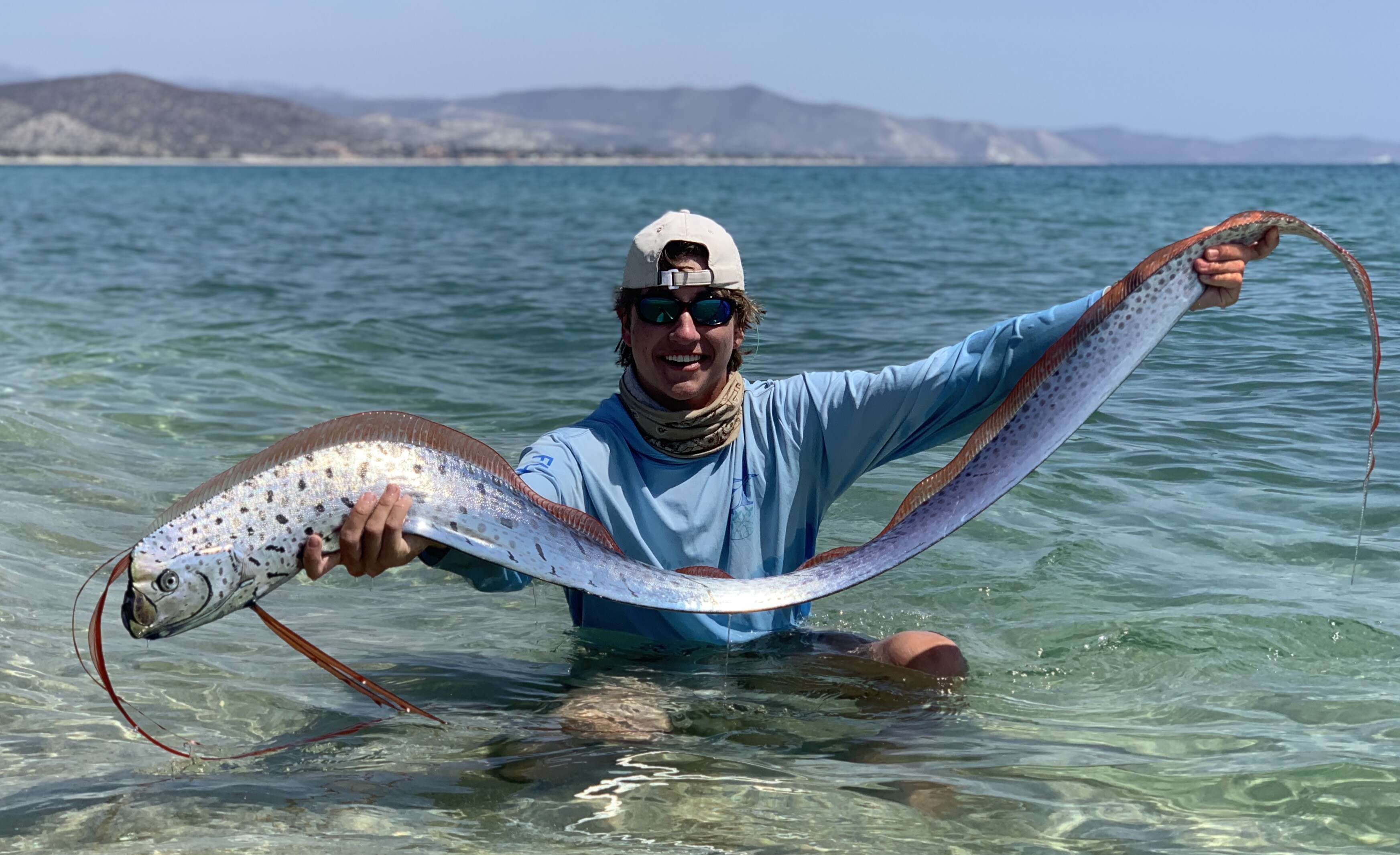 Man holds oarfish in the water to revive him