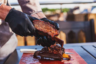 Chef holding cutted juicy slow cooked meat in hands outside